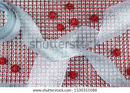 Materials for creativity on a red background: ribbon of rhinestones, ribbon of silver brocade, shamballa beads. Handmade background.
