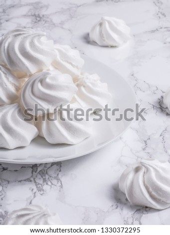 White plate of white meringue kisses on white marble
