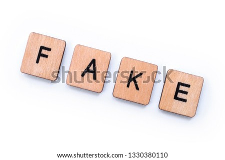 The word FAKE, spelt with wooden letter tiles, over a white background.