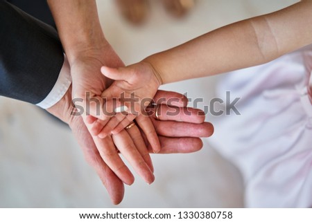 Father, mother and daughter hold hands together