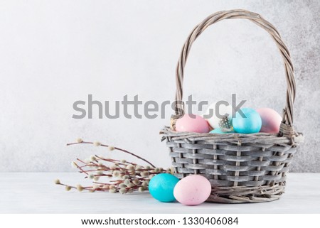 Easter greeting card with pussy willow and colorful easter eggs in basket in front of stone wall. With space for your greetings