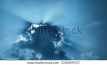 This beautiful photo of the sun hiding behind the clouds, There is so much color in this shot as the light rays poke out from behind these fluffy clouds.