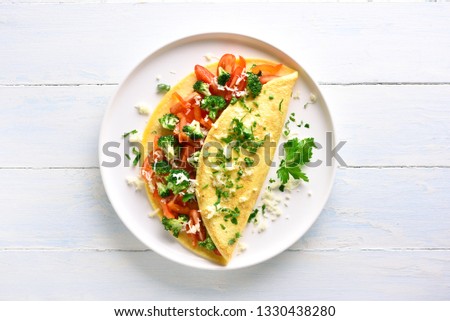 Stuffed omelette with tomatoes, red bell pepper and broccoli on light wooden background with copy space. Healthy diet food for breakfast. Tasty morning food. Top view, flat lay. Royalty-Free Stock Photo #1330438280