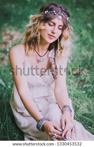 Bohemian hippie woman.
Woman hands with lot of boho style jewelry, blue rings,silver bracelets and henna tattoo. Bohemian hippie white dress.