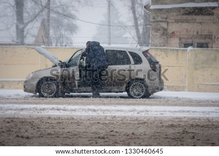 man repairing broken car on the road in snowfall. russia