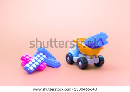 Truck toy model car with blocks of constructor on pink background