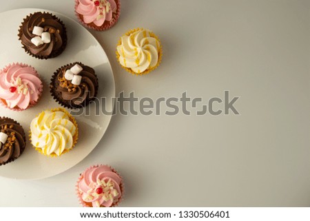 Colorful cupcakes on a white background. Pink, yellow and chocolate cupcakes. Party food. Sweet dessert or breakfast. Party, birthday food. Bright food photo. Copy space.