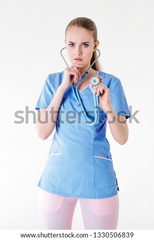 
Woman doctor blonde young light gray background studio day beautiful one purple lilac clothes stethoscope listen bad news sadness. Disease patient. Vertical shot.
