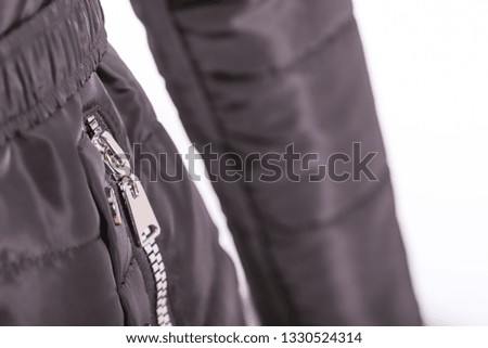 Close up of zipper on black jacket, winter fashion outfit. Jacket isolated on white background.
