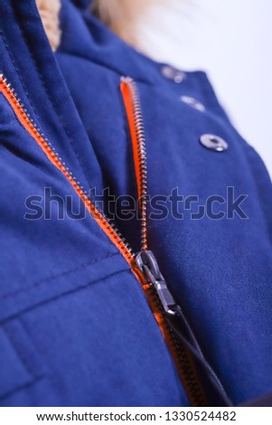 Close up of zipper on blue jacket with fur , winter fashion outfit. Jacket isolated on white background.