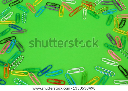 Colorful paper clips on green background. Place for your text.