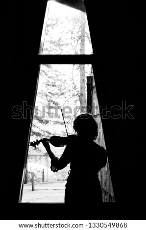 
black and white picture of a girl facing her back playing violin, girl playing violin facing the window