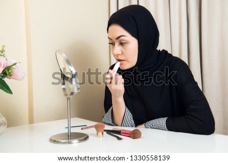Portrait of beautiful muslim woman with hijab applying lipstick