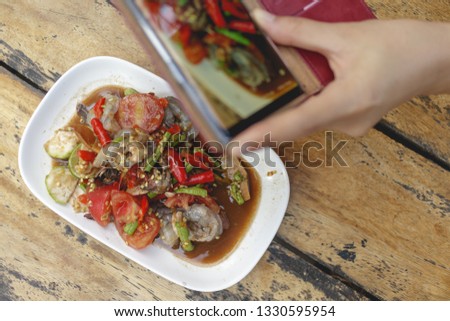 Woman hands takes photograph of local Thai food on table with smartphone