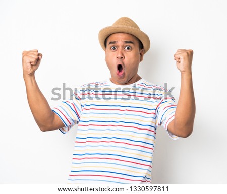 Happy young asian man celebrates with two hand in the air on isolate white background. Royalty-Free Stock Photo #1330597811