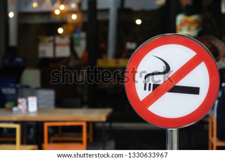 No smoking signpost infornt of a restaurant, piblic outdoor area.