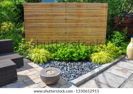Beach pebbles, square cut flagstone and brick landscape pavers and simple plantings provide ample texture and contrast in this small contemporary backyard Asian inspired urban garden. Royalty-Free Stock Photo #1330652915
