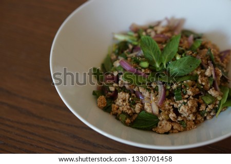 Homemade healthy Thai food Spicy Minced Pork Salad or called Larb Moo in white plate on brown table