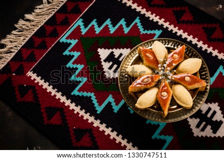 Golden tray with shekerbura and pakhlava for Novruz, Azerbaijan traditional pastry for spring equinox and Persian Nowruz, navruz new year celebration. Ethnic motives rug kilim carpet background 