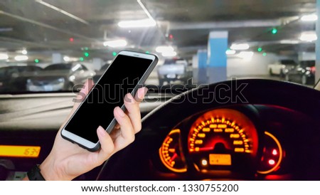 Man use mobile phone in the car, blur image of parking in the building as background.