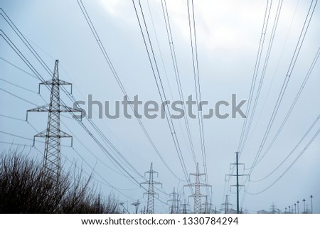 Power lines with lots of wires and metal supports on open water on sky background in spring