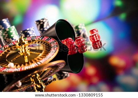 Casino concept. High contrast image of casino roulette, poker chips, cards, dice on gaming table. Bokeh background.