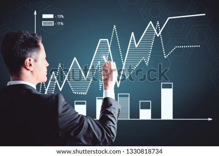 Thoughtful young businessman with glowing business chart hologram on dark background. Trade and finance concept