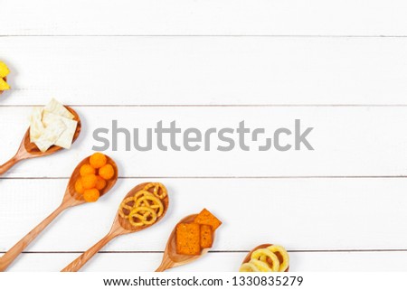 Mix of snacks : pretzels , crackers , chips  and nachos on the table