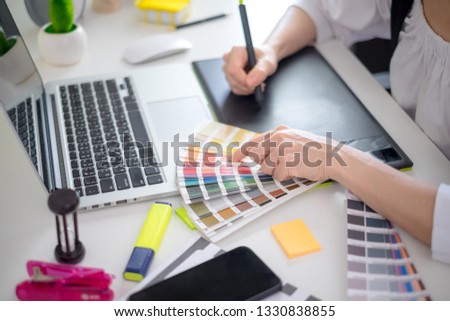 graphic designer working with computer and color swatch. creative woman using digital tablet at modern office. Architect using work tools and sample colour catalog.