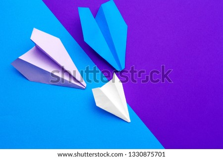 white paper airplane on a blue and purple paper background