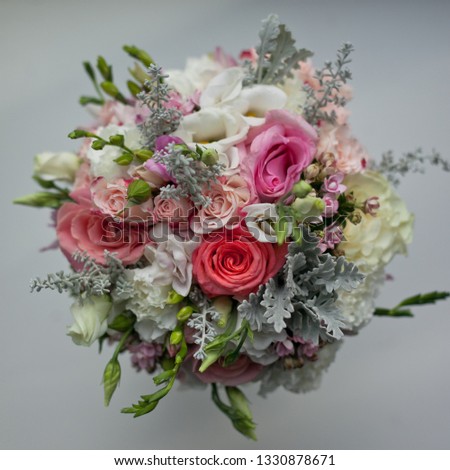 Round bridal bouquet (top view) made of natural flowers in in light colors with greens on a white background