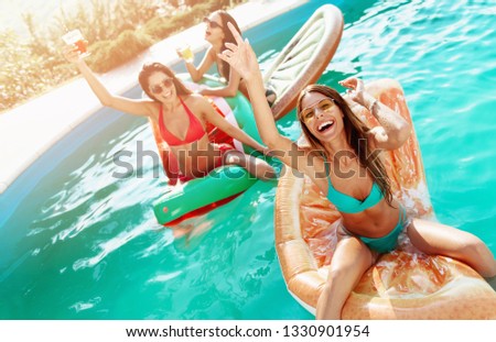 Three girls relaxing and having fun in the pool 
