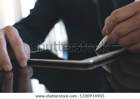 Electronic signature, Business and modern technology concept. Businessman using digital tablet signing electronic document with digital pen on desk with reflection and copy space in office, closeup