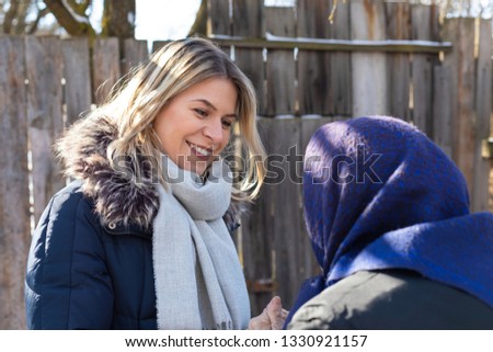 Picture of smiling young woman spending time with old grandmother outdoor