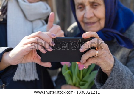 Close up picture of female hands holding a cell phone and taking a selfie - old woman portrait