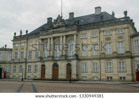 Amalienborg Palace is the home of the Danish royal family in Copenhagen, Denmark. Facade of one of the buildings that make up the complex surrounding the square on a cloudy winter day.