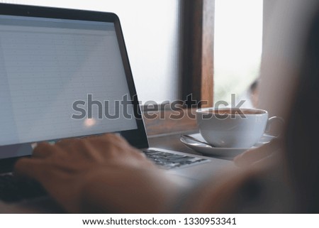 Casual business man, hipster, freelance browsing internet on laptop computer with cup of coffee on wooden table at coffee shop with copy space. Portable office, vintage style