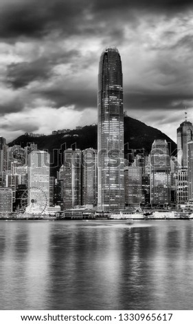 The tallest skyscraper tower on Hong Kong cityscape in Central CBD district against the tallest mountain on a cloudy morning  - high contrast greyscale image of modern urban life.