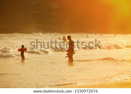 Silhouette of mother enjoying a tropical beach with her children. Travelling with children, beach hopping, family time, beach fun concept. 