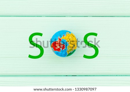 SOS Save the planet concept. The Earth as part word SOS on blue wooden background top view flat lay copy space