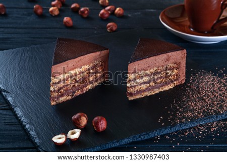 Close up view on sliced hazelnut cake with cacao on a black background and a plate. Flat lay sweets. Picture for menu, background or design with copy space. Sweet dessert. Chocolate cake