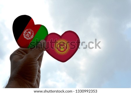 Hand holds a heart Shape Afghanistan and Kyrgyzstan flag, love between two countries