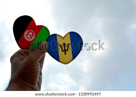 Hand holds a heart Shape Afghanistan and Barbados flag, love between two countries