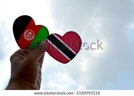Hand holds a heart Shape Afghanistan and Trinidad and Tobago flag, love between two countries