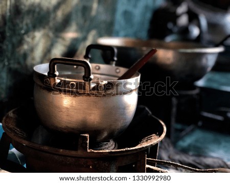 Old pot on dirty stove, in dark kitchen. Morning light. Preparation with breakfast for family. Rustic still life and dark background, dimly light. Selective focus.