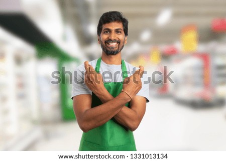 Friendly supermarket or hypermarket indian employee making good luck gesture with crossed fingers and arms in store background