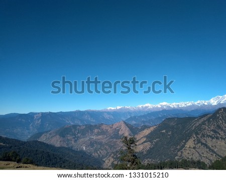 magical view from the top the mountain. This photo is taken in the mountains of chopta(India). This photo has dusty green mountains with a clear sky and wight layer of cloud, And beautiful sun.