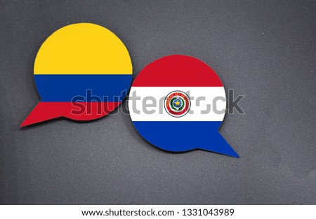 Colombia and Paraguay flags with two speech bubbles on dark gray background