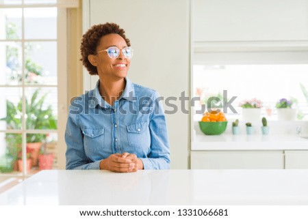 Young beautiful african american woman wearing glasses looking away to side with smile on face, natural expression. Laughing confident.