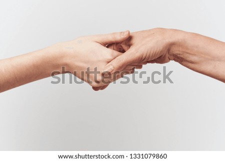 Two female hands hold each other on a gray background